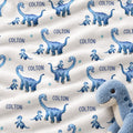 Personalized dinosaur baby boy blanket featuring blue dinosaurs and a custom name on a white background.
