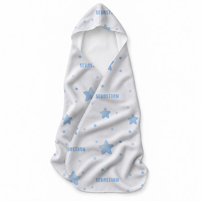 A white baby towel with a hood, decorated with light blue star and dot patterns and personalized with the name 'SEBASTIAN' in blue text.