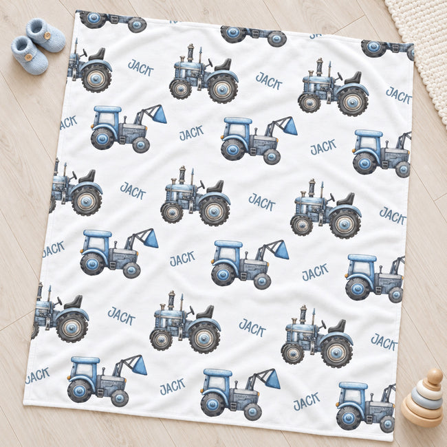 Personalized Blue Tractor Baby Boy Blanket. Blue tractors bring a playful countryside touch to a custom name on a white background.
