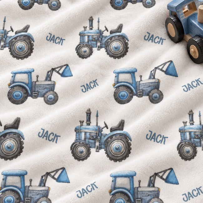 Personalized Blue Tractor Baby Boy Blanket. Blue tractors bring a playful countryside touch to a custom name on a white background.
