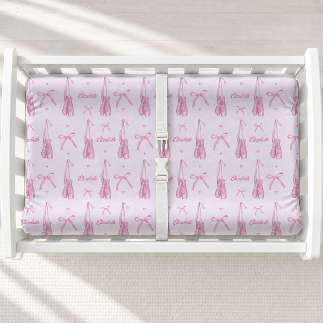 A white changing table with a personalized changing pad cover featuring a pink ballet dancer pattern, including bows, leaping figures, and the name 'Elizabeth' printed in script.