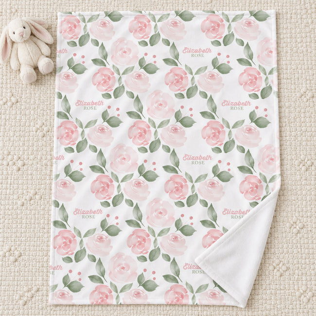 Blush Rose Garden blanket personalized with Elizabeth Rose, laid on a cream rug beside a bunny toy, with one corner folded back.