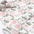 Close-up of Blush Rose Garden baby blanket with pink roses, sage leaves, and Elizabeth Rose lettering beside a plush bunny.