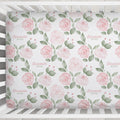 Close-up of Blush Rose Garden crib sheet with pink watercolor roses, sage leaves, and Elizabeth Rose lettering in a white crib.