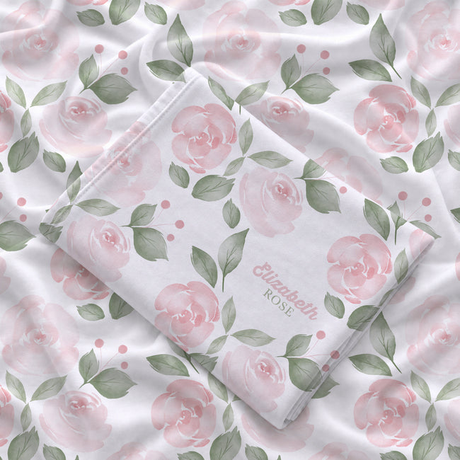 Folded Blush Rose Garden swaddle blanket showing pink watercolor roses, sage leaves, and Elizabeth Rose in pink and green lettering.