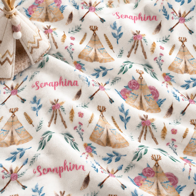Personalized Boho Floral Baby Girl Blanket. Rose-colored flowers, leafy sprigs, feathers, and illustrated teepees surround a custom name in a whimsical boho design.