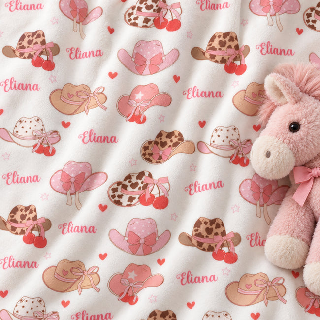 Personalized Cowgirl Hat Baby Girl Blanket. Pink cowgirl hats and sweet bows bring a little western charm to a custom name.