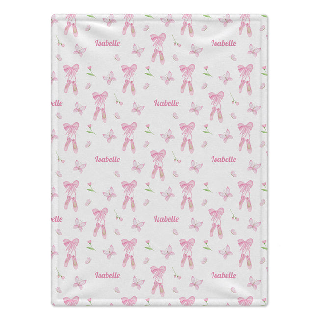 A  blanket with a white background featuring a repeating pattern of pink ballet bows, butterflies, and the name 'Isabelle' in pink script.