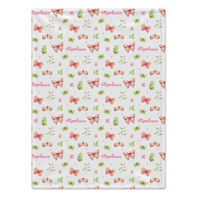Personalized Butterfly and Flower Baby Girl Blanket. Pink, peach, and green butterflies flutter among flowers, leafy sprigs, and tiny hearts around a custom name.
