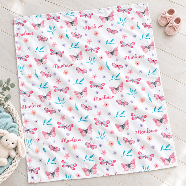 Personalized Pink and Aqua Butterfly Baby Girl Blanket. Pink butterflies, aqua leaves, and delicate flowers surround a custom name on a bright white background.