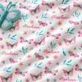 Personalized Pink and Aqua Butterfly Baby Girl Blanket. Pink butterflies, aqua leaves, and delicate flowers surround a custom name on a bright white background.