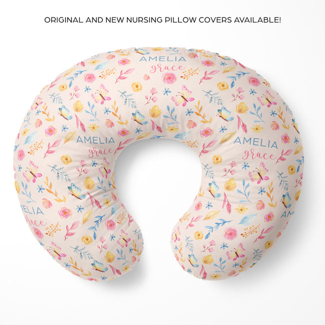 A U-shaped nursing pillow cover with a delicate pastel floral print on a cream background, featuring the personalized name 'AMELIA grace' in blue script. The product is displayed on a clean white background with promotional text at the top.