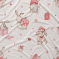 A close-up of a light cream fabric with a repeating watercolor pattern of rabbits, gnomes, and wrapped gifts in soft pink, red, and beige tones.