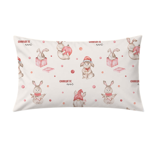 A rectangular pillowcase featuring a repeating watercolor pattern of rabbits, gnomes, books, and pink polka dots on a warm off-white background. The text 'CHARLOTTE and' is printed in a small red font.
