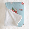 A personalized baby blanket with a light blue printed side featuring a red truck, bunny, tree, and the name 'SIENNA rose', paired with a soft white sherpa reverse, displayed on a white faux fur background.