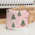 A pink baby blanket with a Christmas tree pattern and the name 'CHARLOTTE' printed on it, styled in a nursery setting next to a woven basket.