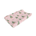 A pink changing pad cover featuring a watercolor Christmas tree and cabin pattern, shown on a clean white background.
