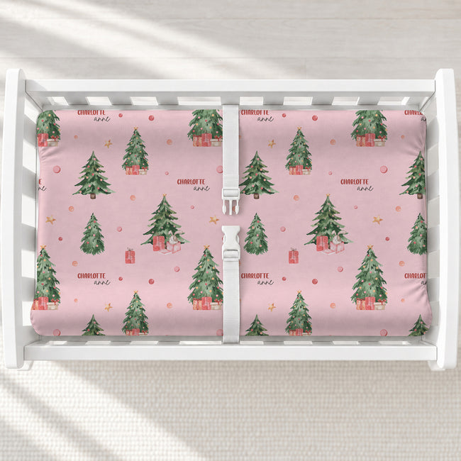 A white changing table with a personalized changing pad cover featuring a Christmas tree pattern.