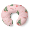 A U-shaped nursing pillow in light pink with a watercolor Christmas tree and gift print, featuring the personalized name 'CHARLOTTE ann' in red and black script.
