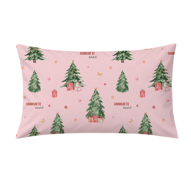 A rectangular pink pillow sham featuring a watercolor Christmas tree pattern with red gift boxes, gold stars, and the text 'CHARLOTTE love' repeated across the design.