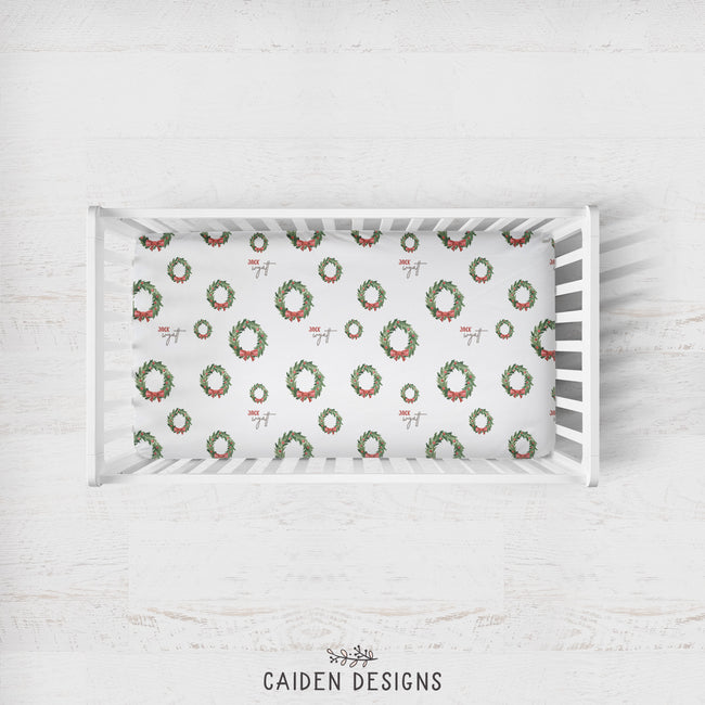 Personalized Christmas wreath crib sheet with evergreen branches, red bows and optional baby name