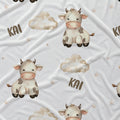 White baby bedding set featuring a repeating pattern of cute cartoon cows, fluffy clouds, small stars, and the name 'KAI' in brown lettering.