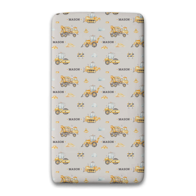 A fitted sheet, featuring a repeating pattern of yellow construction vehicles and the name 'MASON' on a light gray background.