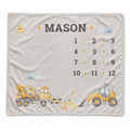 A personalized baby blanket featuring construction vehicles, clouds, and the name 'MASON' with a numbered grid from 1 to 12, shown flat against a white background.