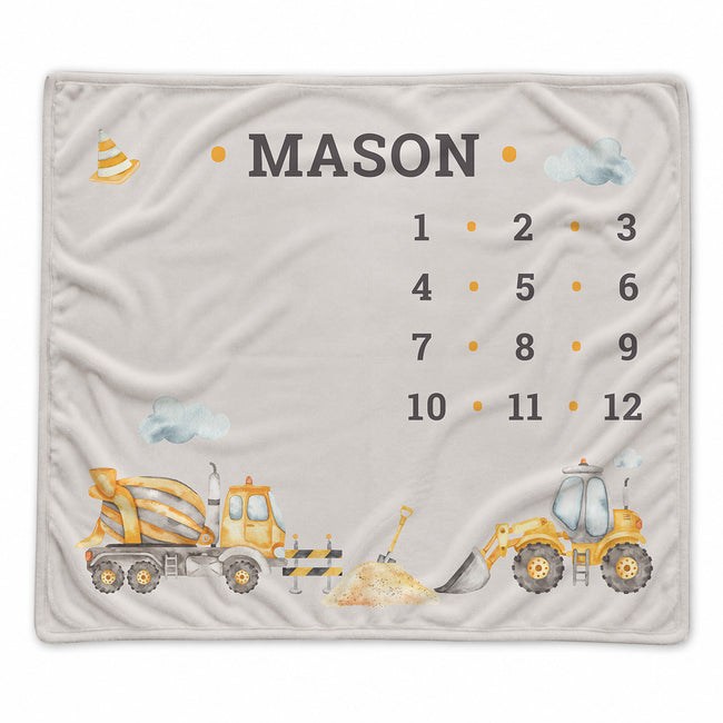 A personalized baby blanket featuring construction vehicles, clouds, and the name 'MASON' with a numbered grid from 1 to 12, shown flat against a white background.