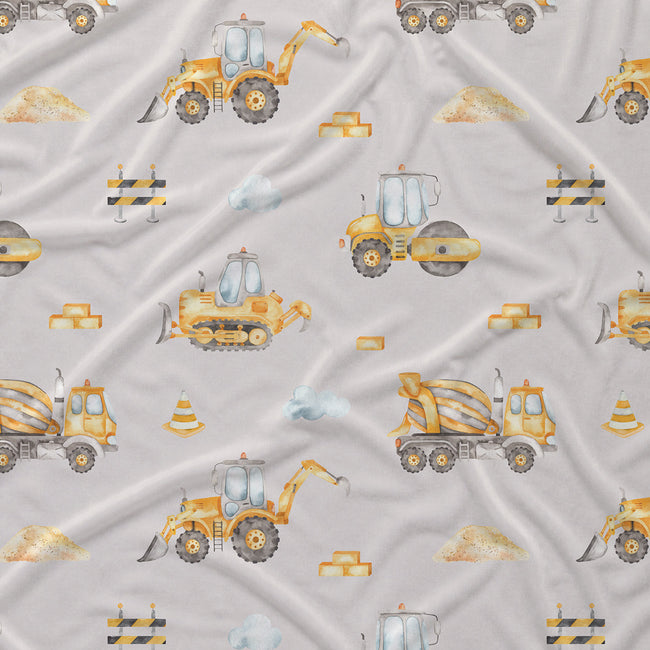 Light gray fabric with a repeating pattern of yellow construction vehicles, including excavators, bulldozers, a cement mixer truck, road rollers, barriers, and small traffic cones.