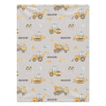 A rectangular baby blanket with a light gray background and a repeating construction-themed pattern featuring yellow and orange excavators, bulldozers, road rollers, traffic cones, and the name 'MASON' printed in black.