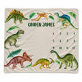 Personalized dinosaur baby milestone blanket with watercolor dinosaurs, tropical leaves, custom name, and months 1–12