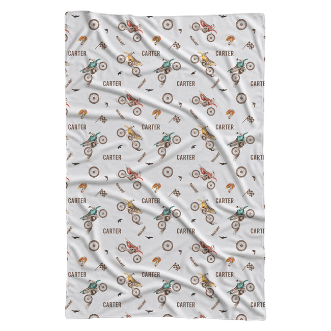 A white baby blanket featuring a repeating pattern of vintage-style BMX bicycles and the name 'CARTER' in brown text.