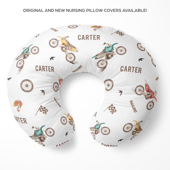 A U-shaped nursing pillow cover with a white background and a repeating pattern of vintage-style dirt bikes and the name 'CARTER' in brown. The text 'ORIGINAL AND NEW NURSING PILLOW COVERS AVAILABLE!' is printed at the top of the image.