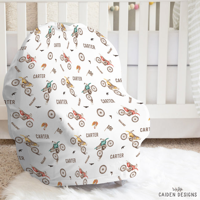 A personalized infant car seat cover featuring a dirty bike pattern with the name Carter on it