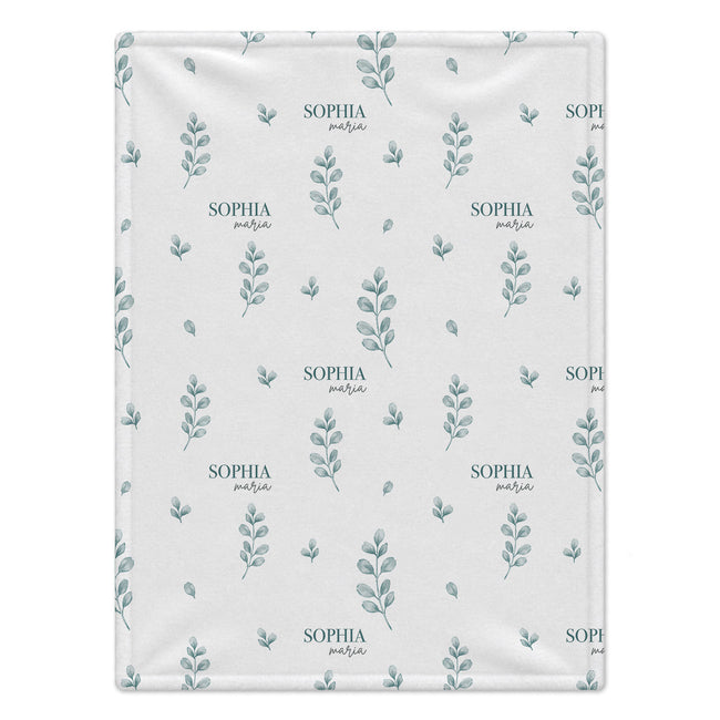 A square baby blanket with a repeating pattern of muted blue-green leafy sprigs and the text 'SOPHIA Maria' on a warm off-white background.