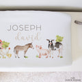 A white personalized baby changing pad printed with text reading 'JOSEPH david' above a farm animal illustration including a donkey, pig, cow, and chicken.