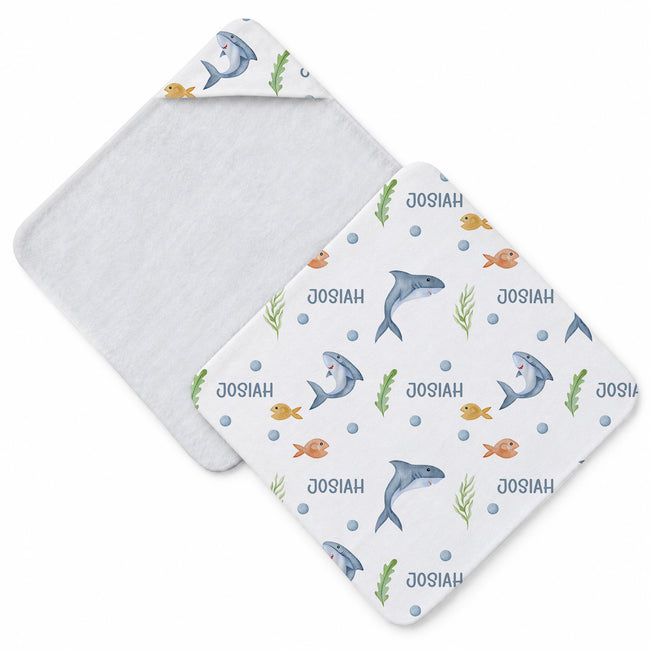 White hooded towel featuring blue sharks, yellow and orange fish, green seaweed, blue bubbles, and the name Josiah.