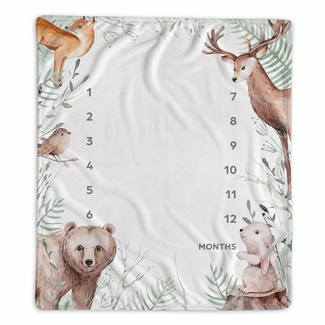 A square baby growth chart blanket featuring watercolor-style woodland animal illustrations including a deer, bear, rabbit, bird, and fox around a large central space marked for months 1 through 12.