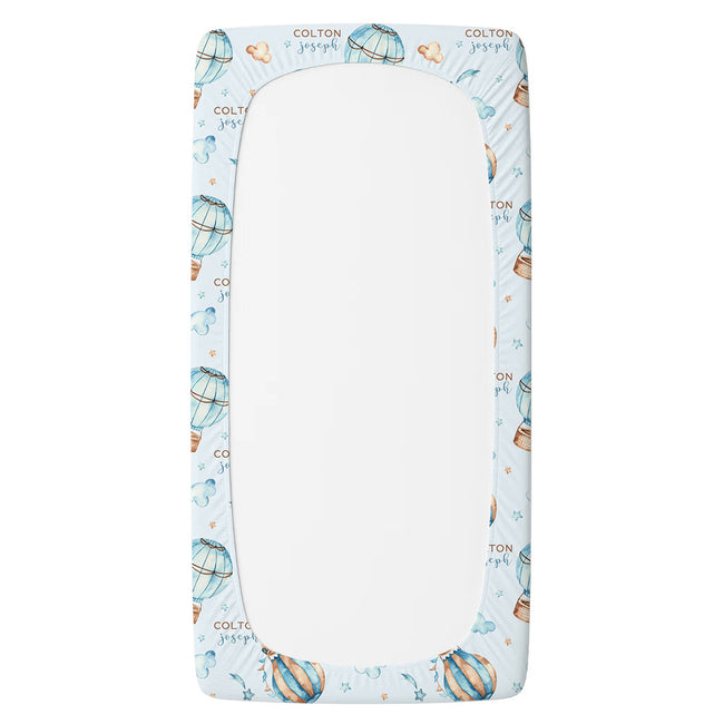 A twin sheet protector with a light blue background and a repeating pattern of hot air balloons, stars, and the text 'COLTON baby'.