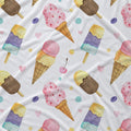 A white fabric surface printed with a repeating watercolor pattern of ice cream cones, popsicles, cherries, and pastel dots in pink, yellow, blue, purple, and brown.