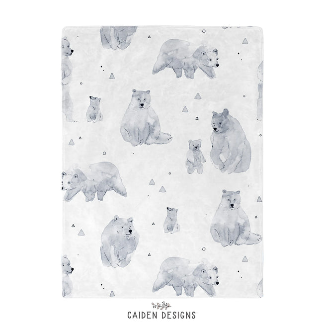 A baby blanket featuring a repeating watercolor-style pattern of polar bears and polar bear cubs in soft gray tones on a white background, with small scattered triangle and circle motifs. The brand name 'CAIDEN DESIGNS' appears at the bottom.