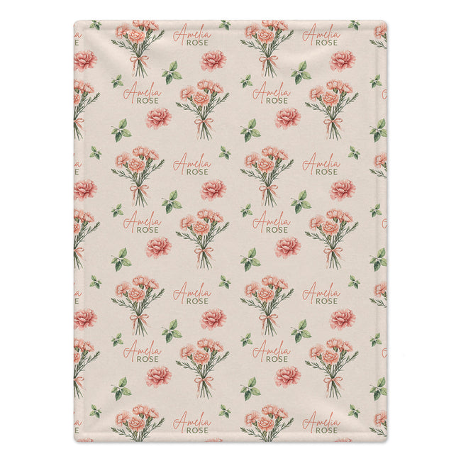 Cream blanket with peach-pink carnation bouquets, green leaves, and the name Amelia Rose in coral and green lettering.