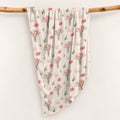 Cream swaddle blanket with peach-pink carnation bouquets, green leaves, and the name Amelia Rose in coral and green lettering.