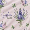 A fabric swatch featuring a watercolor floral pattern with purple and pink Larkspur flowers, green leaves, and the text 'Sophia KATE' in blue and green script on a light blush pink background.