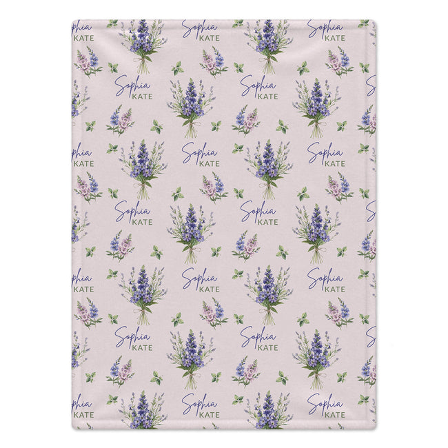 Pale blush blanket with blue and lavender larkspur bouquets, green leaves, and the name Sophia Kate in blue and green lettering.