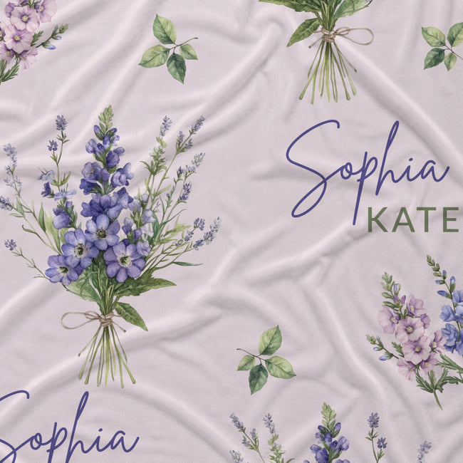 Personalized fabric featuring a watercolor floral pattern with purple and lavender bouquets, green leaves, and the names 'Sophia' and 'KATE' printed on a light blush pink background.
