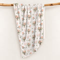 Ivory swaddle blanket with peach rose bouquets, scattered green leaves, and the name Isabella Rose in coral and green lettering.