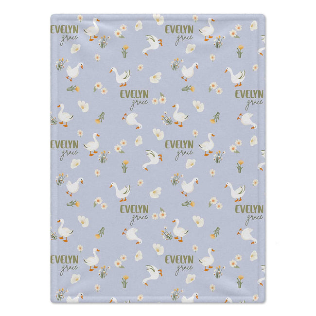 Personalized Goose Baby Girl Blanket. White geese and delicate flowers surround a custom name on a soft lavender background.