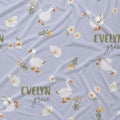 Light lavender fabric with a repeating pattern of white geese, small white flowers, green stems, and the words 'EVELYN grace' in muted olive green and dark script.